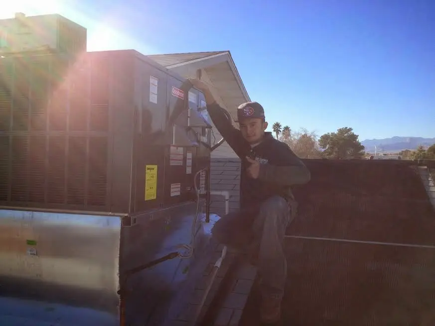 HVAC technician performing AC Tune-Up on a rooftop unit in East Milton